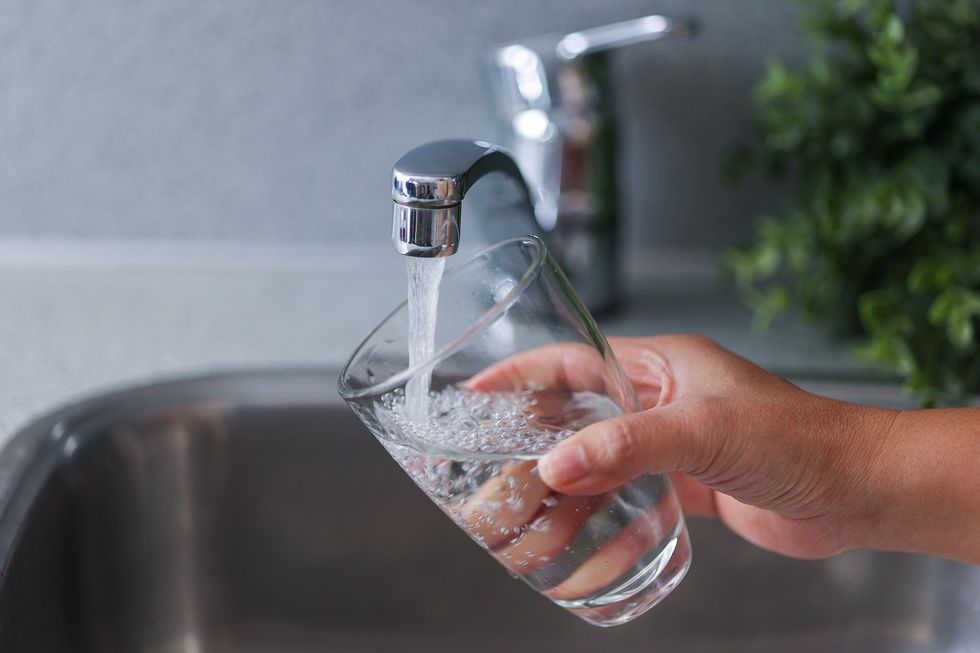 curiocity calgary woman filling water glass from tap