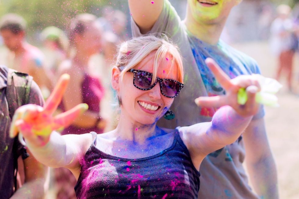 Portait of girl stained with colorful powder smiling during Holifest
