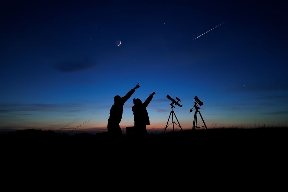 Amateur astronomers looking at the evening skies, observing planets, stars, Moon and other celestial objects with a telescope and camera on a star tracker.