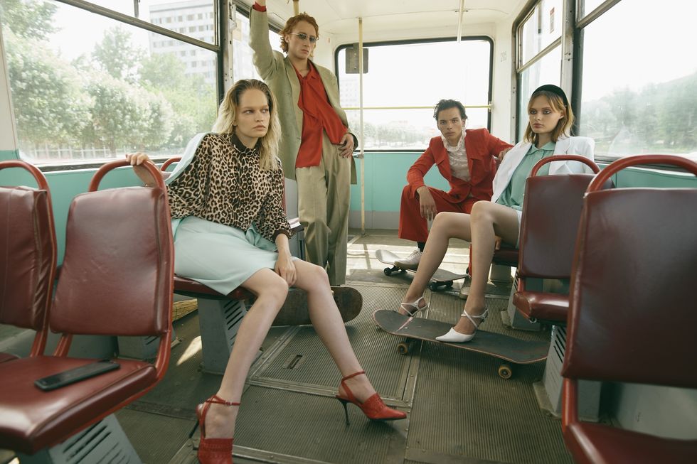 Models posing wearing vintage clothing on a bus.