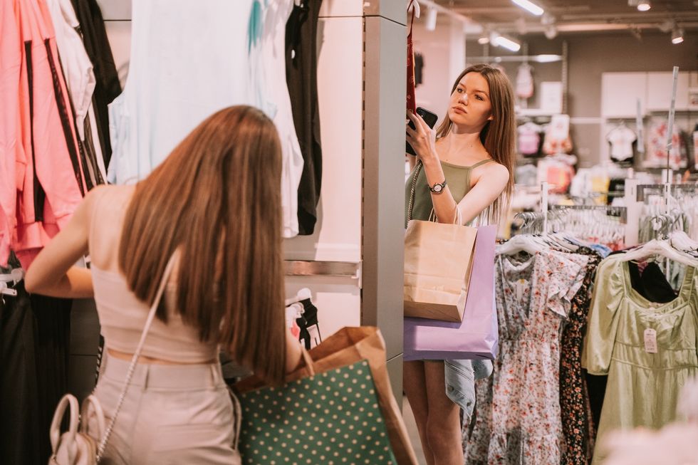 girls with shopping bags in the shop looking trough the clothes