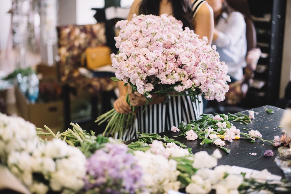 Flower shops Young florist woman working, sorting fresh delivery of tender pink matthiola flowers at the florist shop