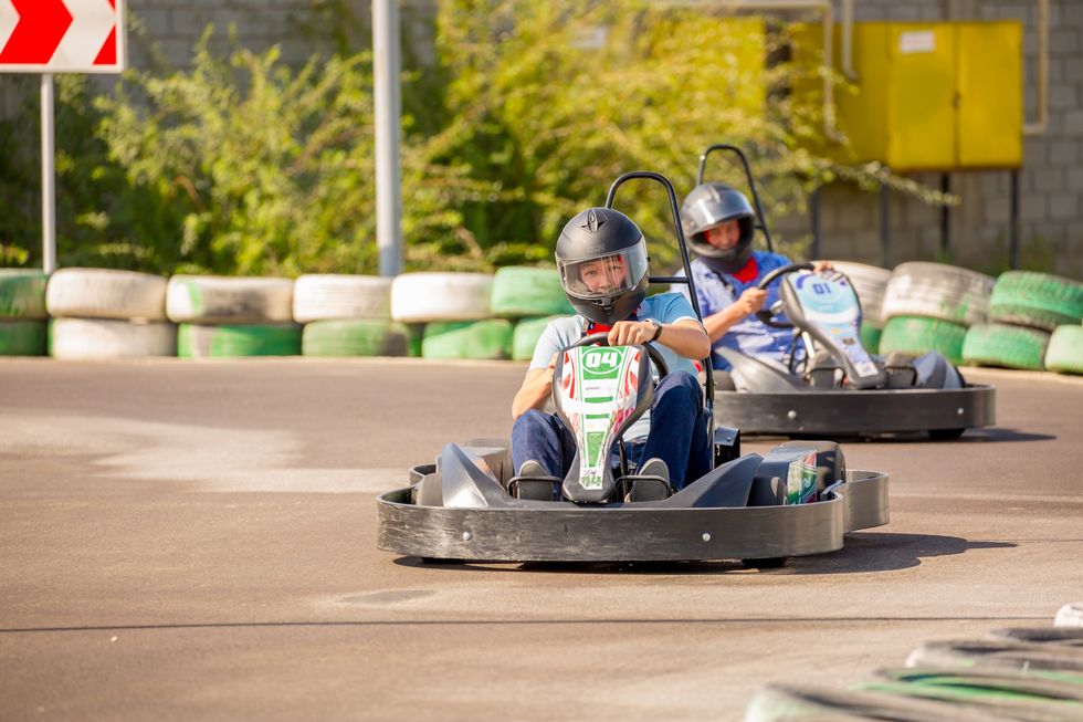 Men in gear and helmet driving a go-kart.