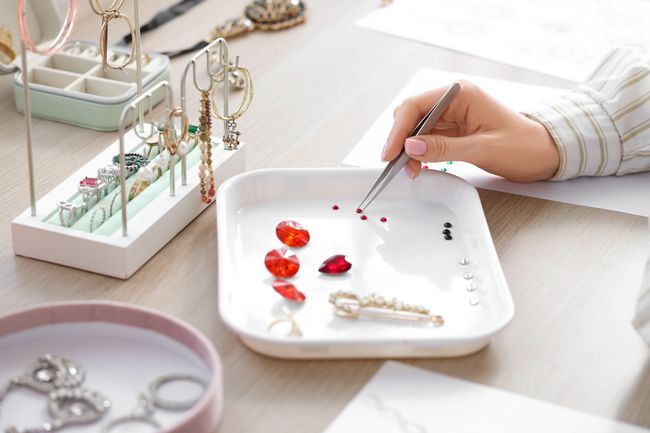 Female jewelry designer working with gems at table in workshop, closeup
