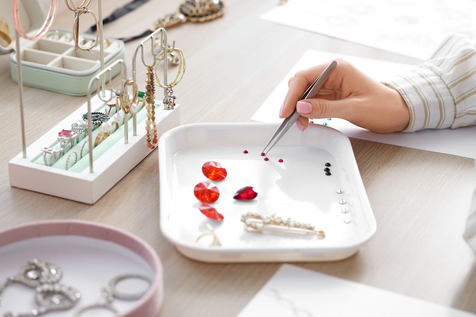 Female jewelry designer working with gems at table in workshop, closeup
