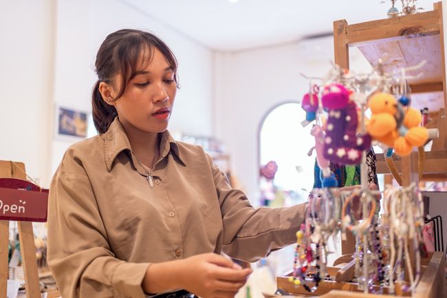 woman examining handmade jewelry inside a boutique shop.