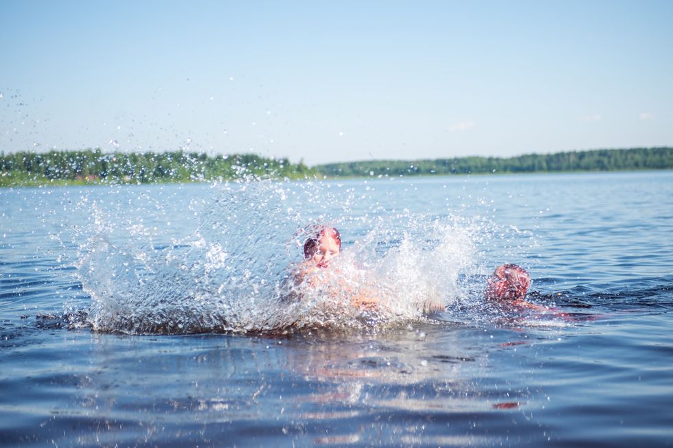 People frolic and swim in the lake on a hot sunny summer day.