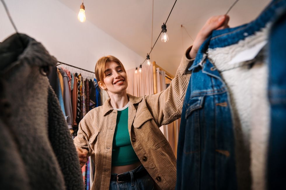 A Fashionable Young Woman Enthusiastically Shopping for Vintage Clothes in a Trendy Store