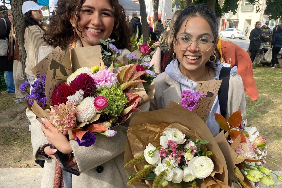 two people holding bouquets of flowers at the market