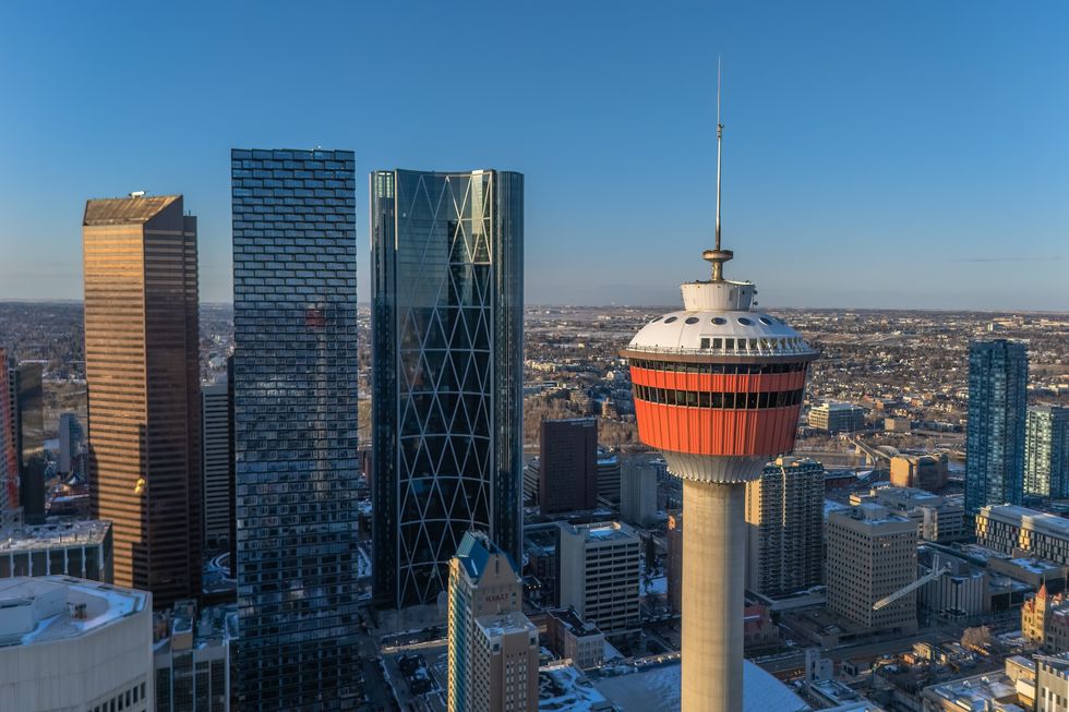 High angle view of the Calgary Tower and downtown skyline with modern skyscrapers at sunset.