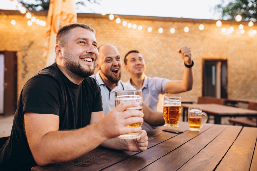 Friends drinking beer together at pub and watching football Friends drinking beer together at pub and watching football