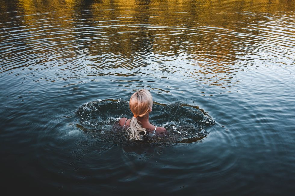 woman stands in the river water before entering for a swim