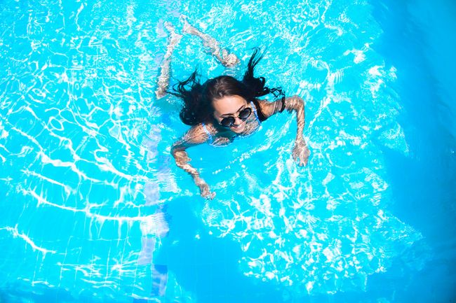 girl in sunglasses is swimming in the pool