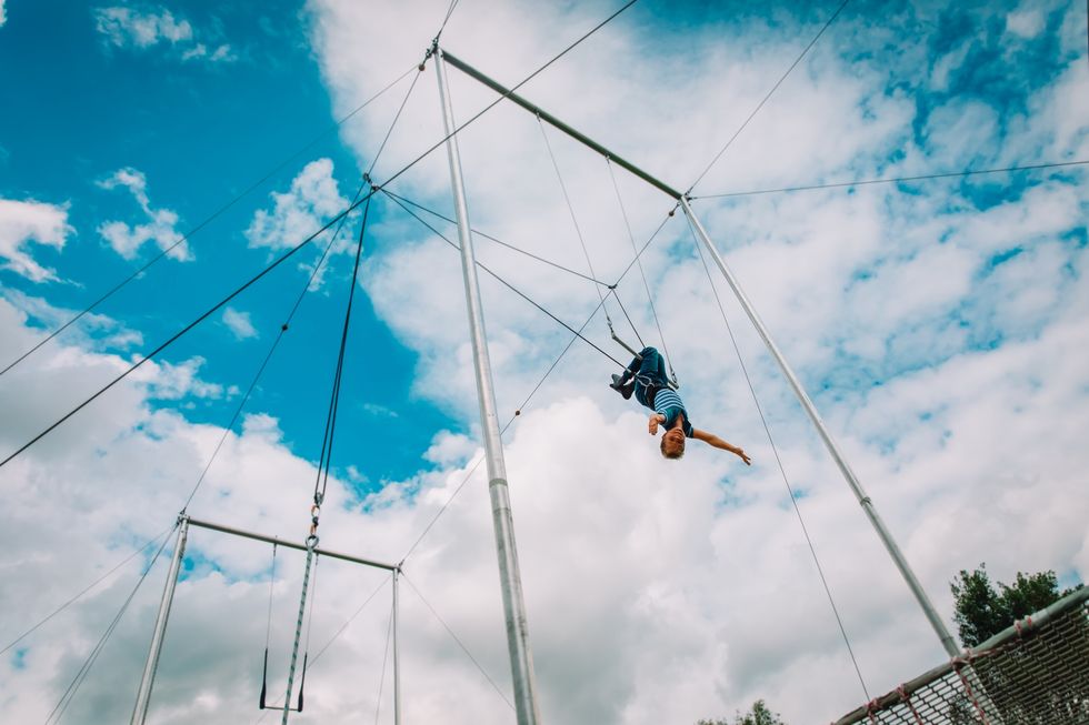 kid having swing on a high flying trapeze, boy learning acrobatic kid having swing on a high flying trapeze, boy learning acrobatic