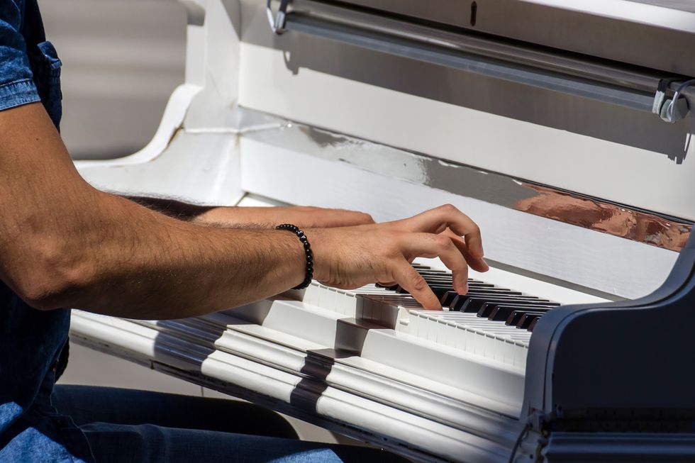 Man playing a white piano in the summer sun