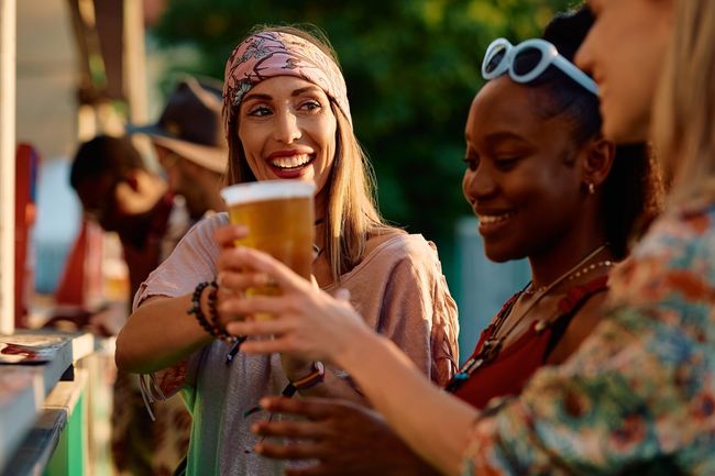 Happy woman and her friends buying beer during summer music festival.