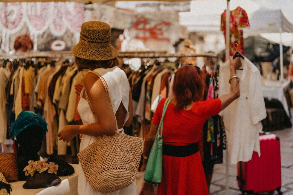 People browsing vintage clothing at an outdoor flea market in Milan Navigli, sustainable fashion and street shopping lifestyle.
