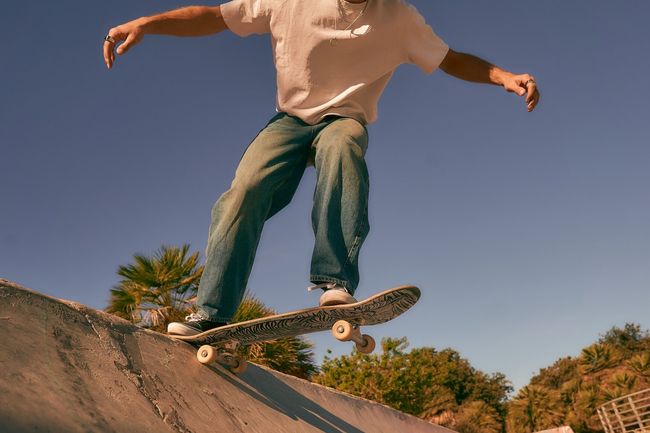 Close up of young man doing tricks on his skateboard at the skate park. Active sport concept