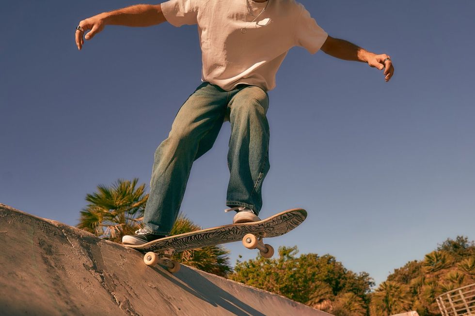 Close up of young man doing tricks on his skateboard at the skate park. Active sport concept