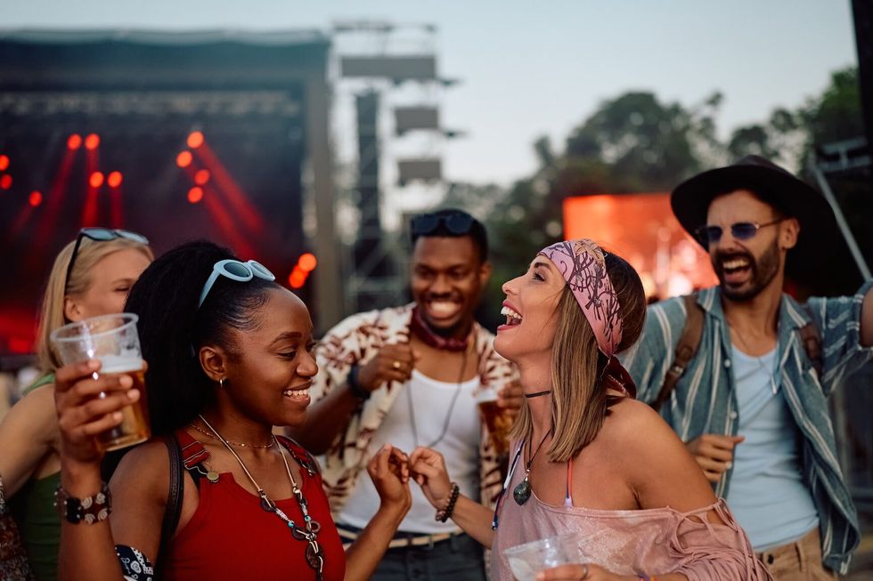 Happy friends dancing and having fun at summer music festival.