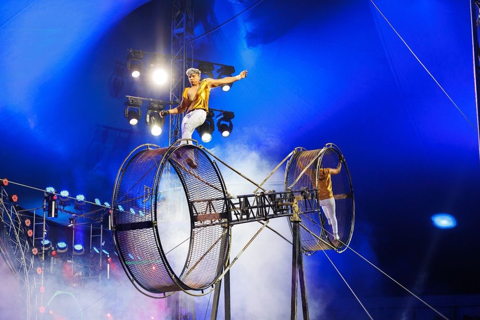 Brave male acrobats in the rotating wheel of death perform under the dome of the circus
