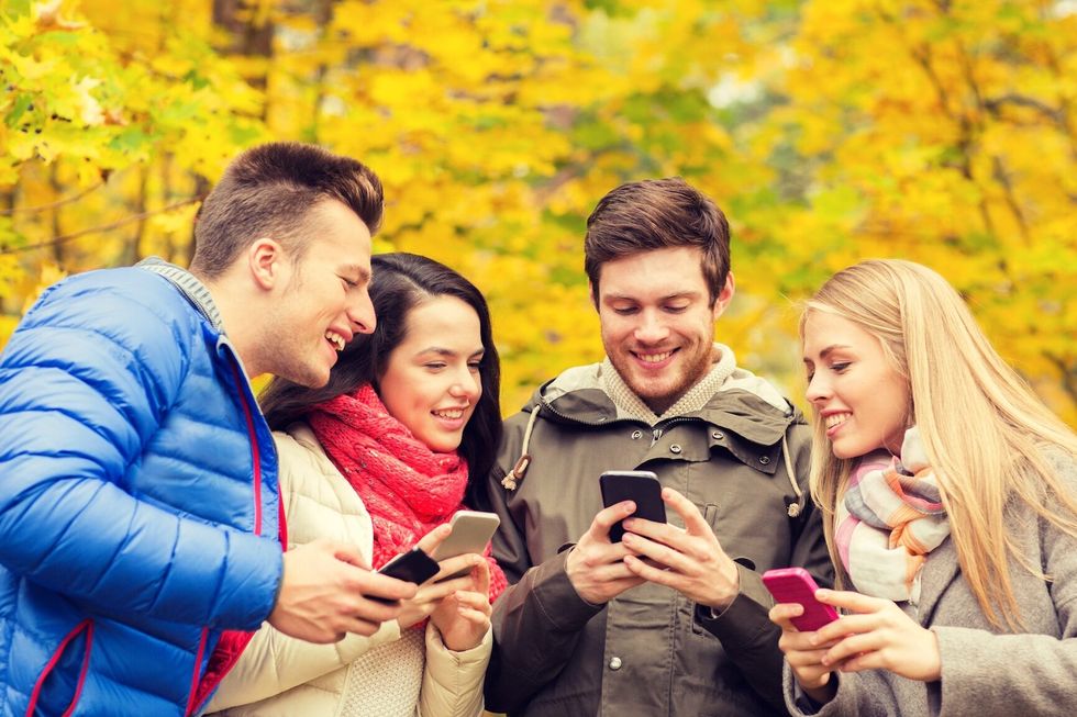 season, people, technology and friendship concept - group of smiling friends with smartphones in autumn park