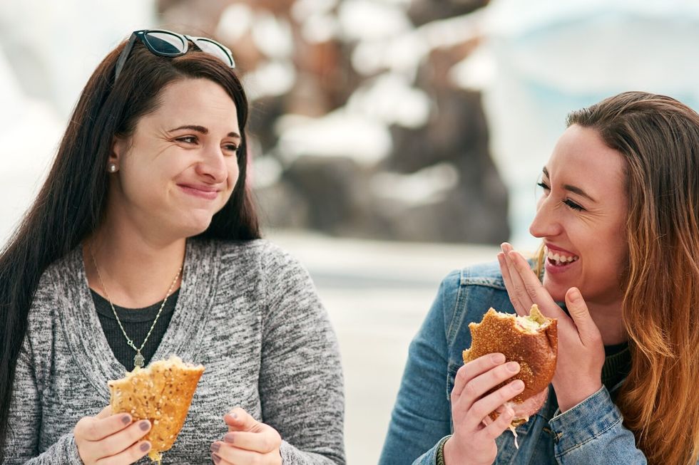Women, friends and eating sandwich in city, park