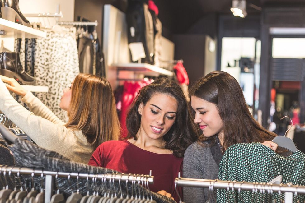 27 Boutique Three women in a clothing store choosing a dress. Girls are on their early twenties, they are happy about shopping, consumerism concept.