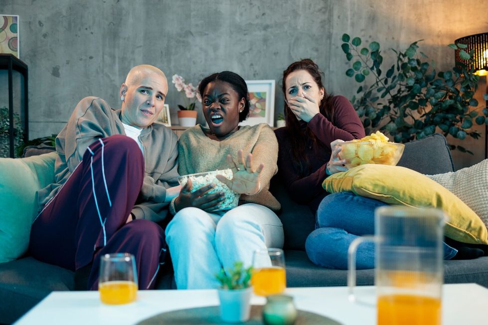 friends watching a scary movie at home, expressing fear and shock