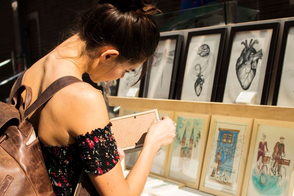 woman choosing a drawing or a painting to buy at a market place.