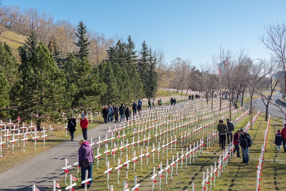 People visit crosses lined up row by row along Memorial Drive to commemorate the fallen Canadian soldiers that died in battle, located in Calgary, Alberta, Canada