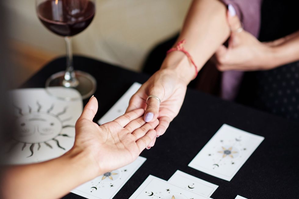 Fortune teller asking young woman to give her hand for palm reading