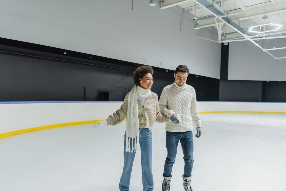 Couple holding hands while skating on indoor ice rink
