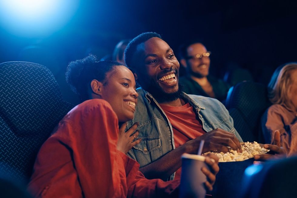 Happy couple enjoying on a date in movie theater.